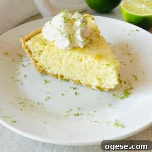 gluten free key lime pie on a plate next to limes topped with whipped cream and lime zest