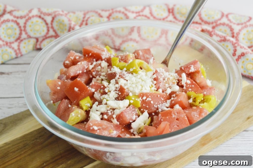 marinated tomato salad with feta in bowl with spoon 