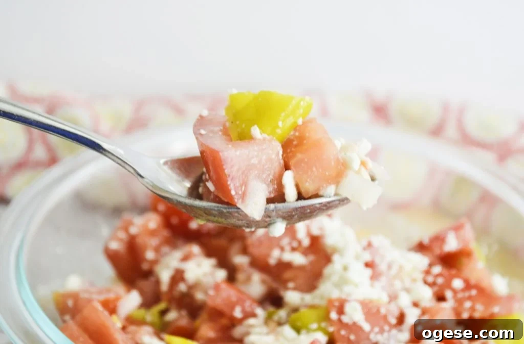 Marinated tomato salad with feta on spoon close up 