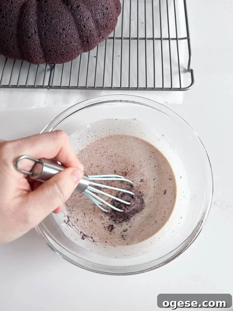 Ultimate Chocolate Overload Cake Recipe for True Chocoholics 9 A hand beginning to whisk heavy cream and chocolate in a glass bowl.