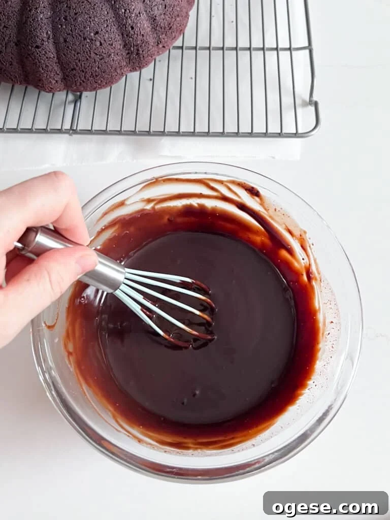 Ultimate Chocolate Overload Cake Recipe for True Chocoholics 10 A hand whisking chocolate ganache in a glass bowl once it's come together.