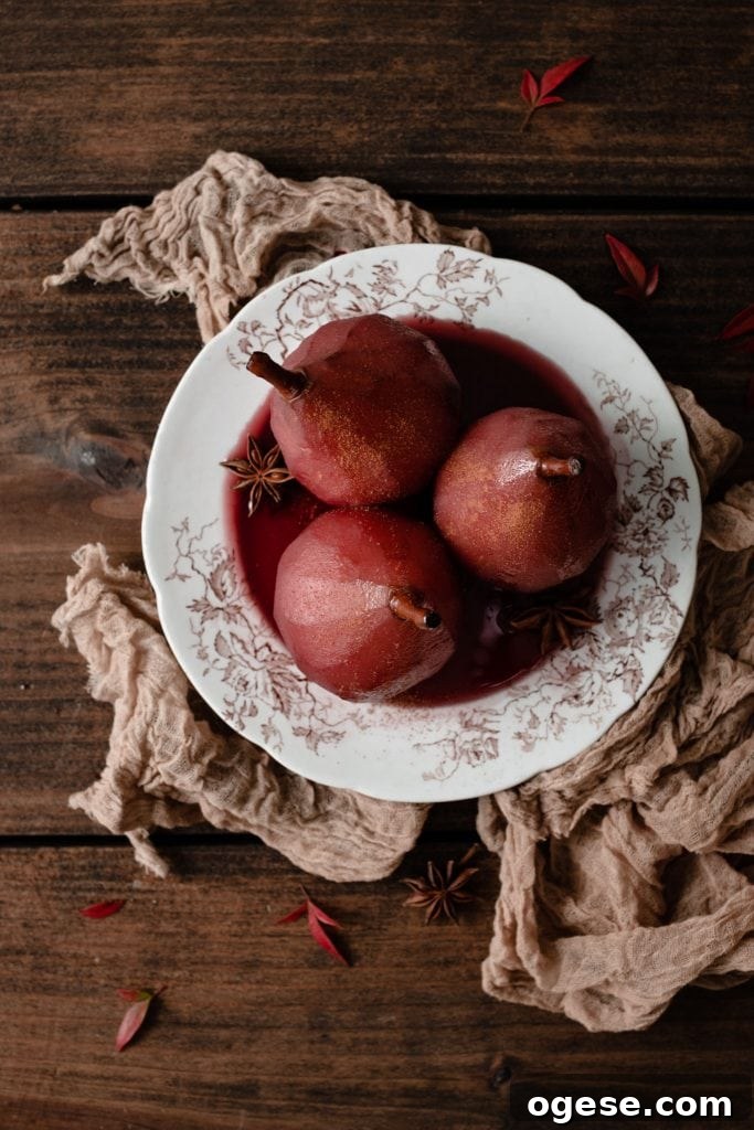 Poached Red anjou pears on plate with red sauce.