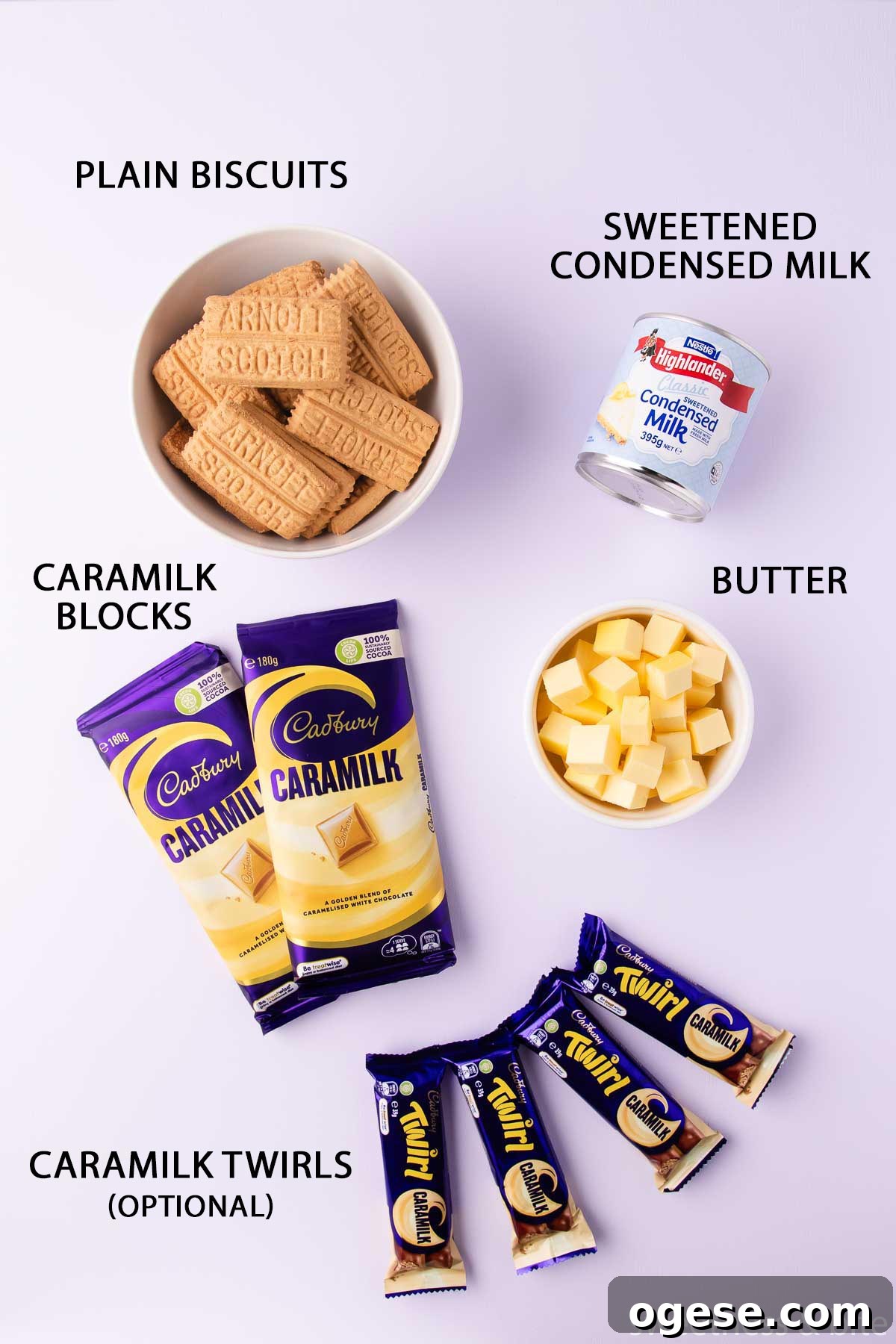 The Caramilk slice ingredients laid out on a light purple background - biscuits, condensed milk, butter, two blocks of Caramilk chocolate and four Caramilk Twirl bars.