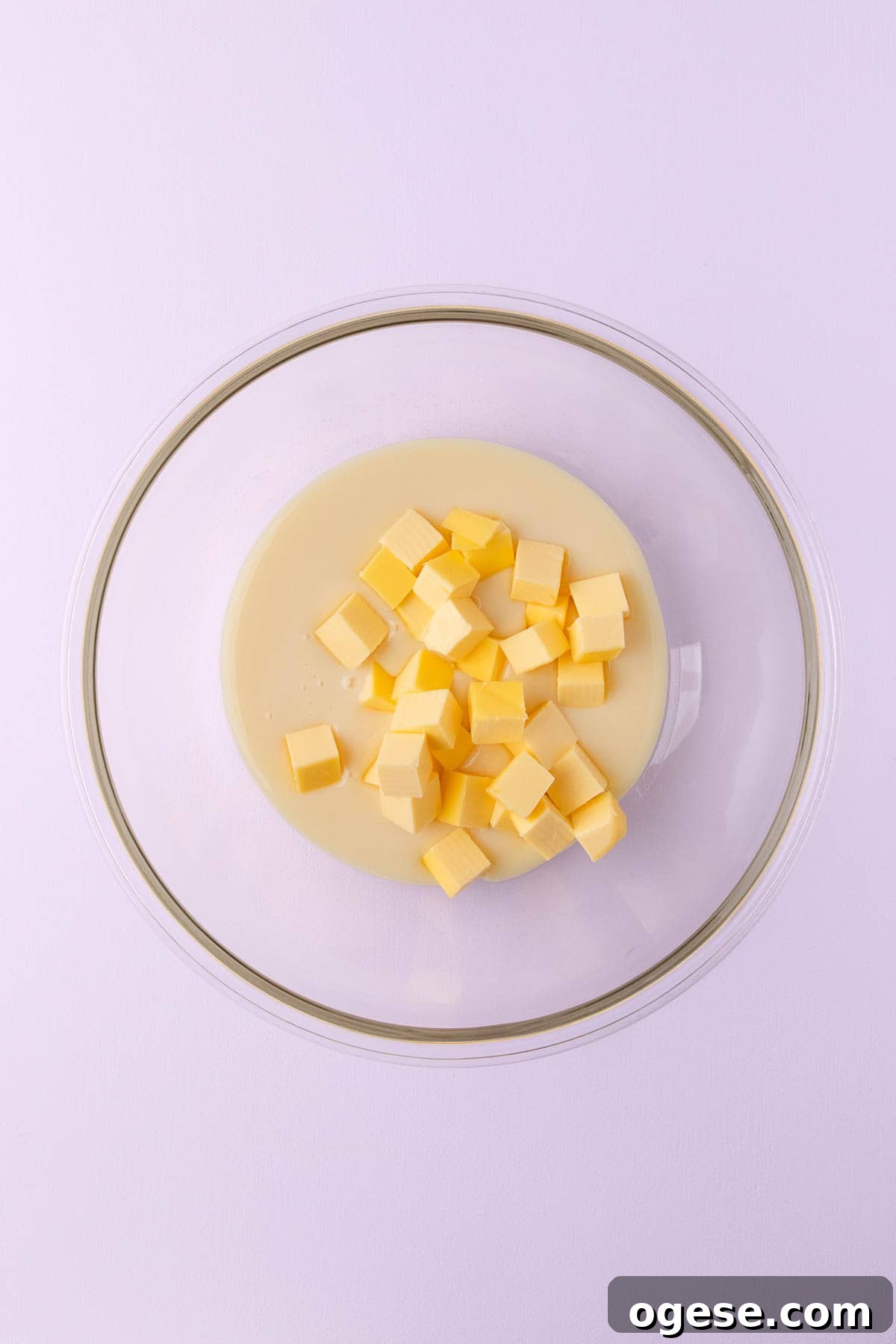 Sweetened condensed milk and chopped butter in a large glass bowl.