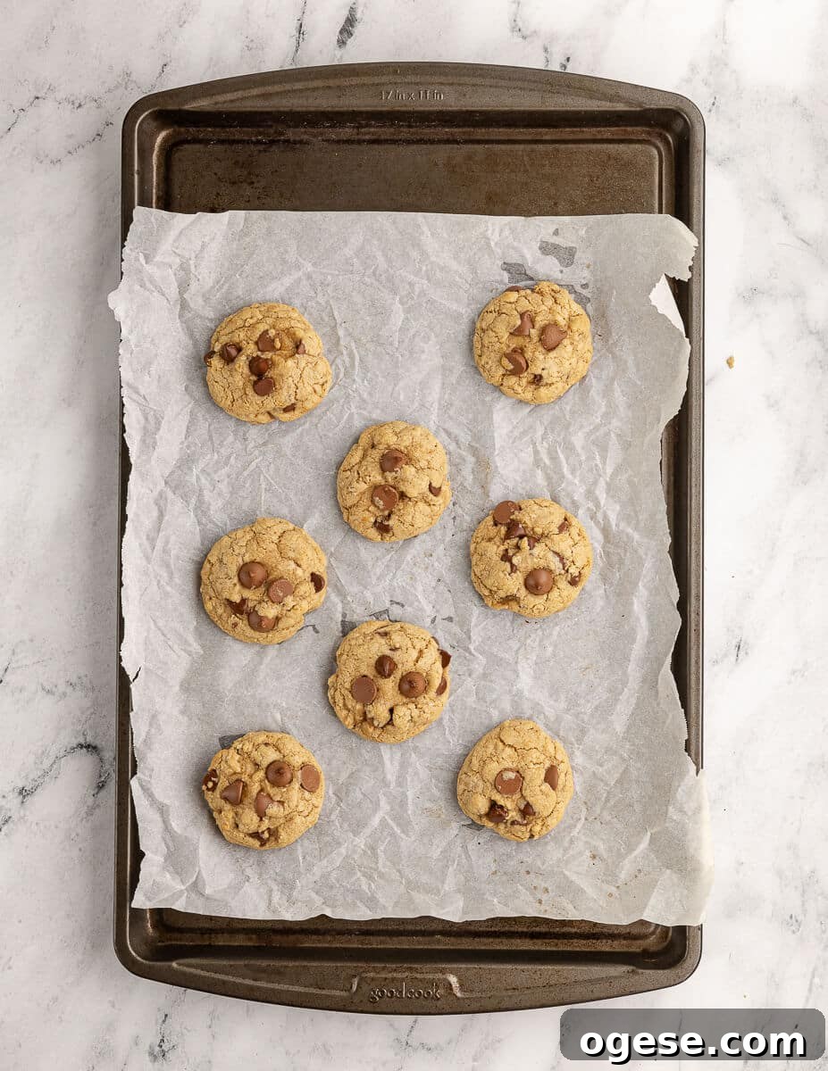 Gluten-Free Chocolate Chip Cookie Recipe You’ll Love 13 baked gluten free chocolate chip cookies on a sheet pan with parchment paper.