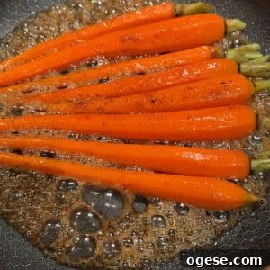 Ale’s Top Easter Recipes 2026: Festive Ideas for Your Holiday 9 Bright orange carrots being sautéed in a frying pan with bubbling brown sauce. The carrots are evenly spaced, and the sauce appears to be well-seasoned with black pepper.