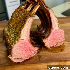Ale’s Top Easter Recipes 2026: Festive Ideas for Your Holiday 10 A perfectly cooked rack of lamb cut into two sections, displaying a pink, juicy interior and seasoned crust, resting on a wooden cutting board in a kitchen setting.