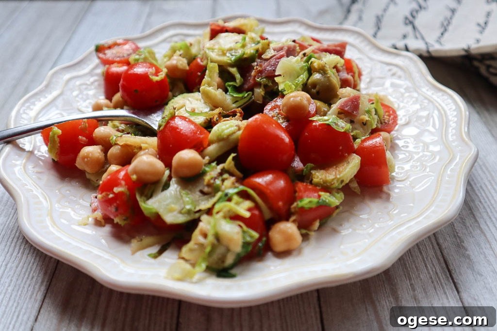 white plate with sauteed brussels sprouts with beans, deli meat, tomatoes, and olives.
