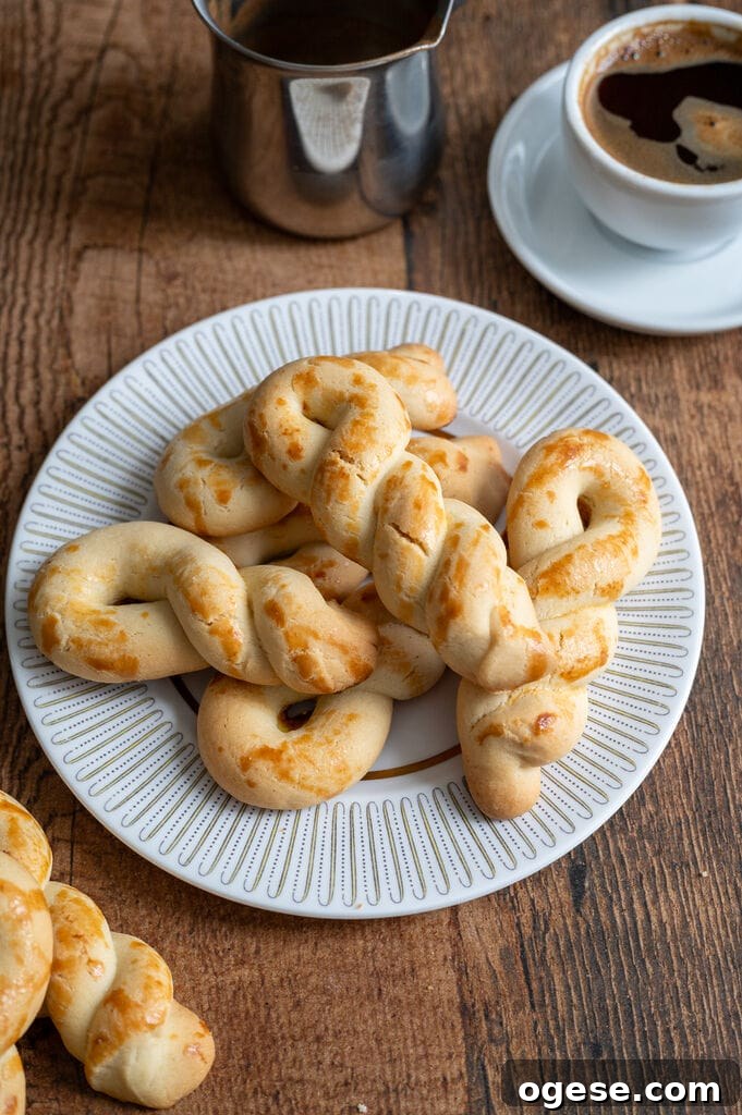 Greek Butter Koulourakia Cookies with Chocolate Swirl 22 Greek butter koulourakia on a white plate with gold decor, next to a cup of Greek coffee.
