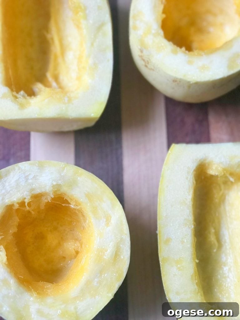 How to Prepare Spaghetti Squash: Simple Steps + Tasty Recipes 5 4 Raw Spaghetti Squash halves sliced and on a cutting board