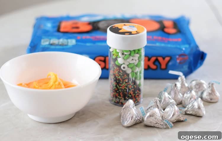 bowl of frosting, bottle of sprinkles, Hershey kisses and a package of oreo cookies
