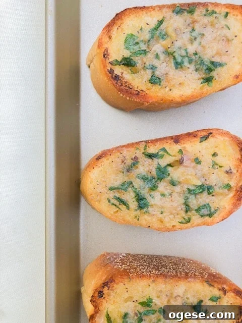 Garlic bread on a baking sheet with parsley.