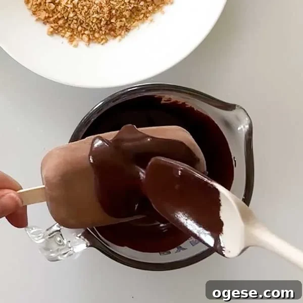 Chocolate Peanut Butter Cottage Cheese Ice Cream Bars — High-Protein Treat 12 Spreading the melted chocolate over the frozen popsicle with a spatula.
