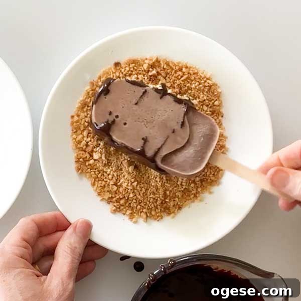 Chocolate Peanut Butter Cottage Cheese Ice Cream Bars — High-Protein Treat 13 Dipping the chocolate into the chopped peanuts in a white dish.
