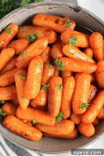Air fried roasted baby carrots in a gray serving bowl with a serving spoon.