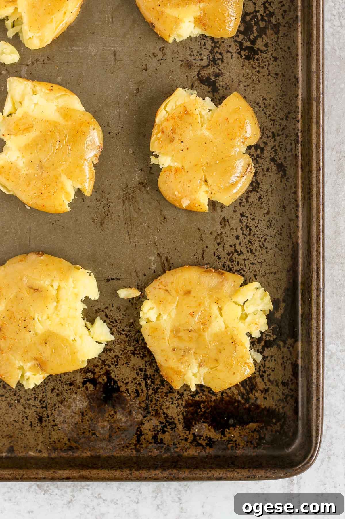 Potatoes that have been smashed on a baking sheet.