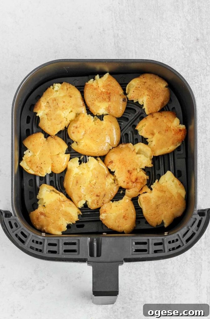 Air fryer basket with pre-fried smashed potatoes.