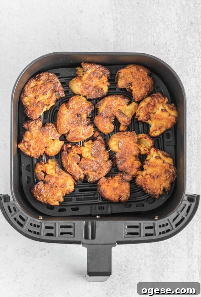 Fried smashed potatoes in an air fryer basket.