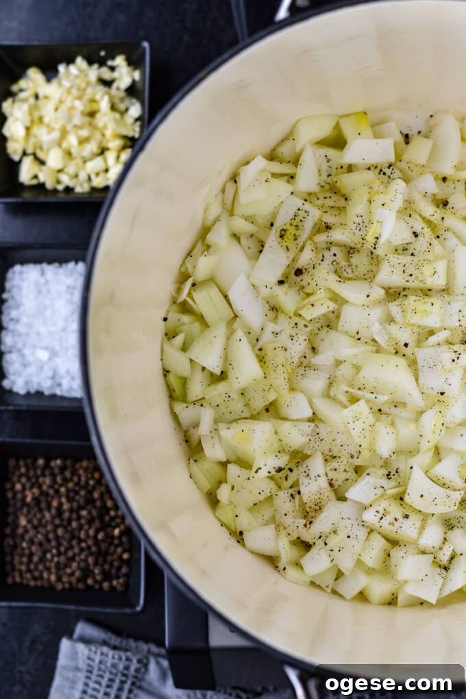 Authentic Homemade Pasta Sauce Recipe for Rich, Simple Flavor 3 A Dutch Oven with sauteed chopped onions. Small black prep bowls hold chopped garlic, salt and pepper.