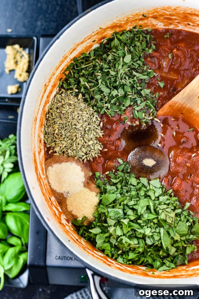Authentic Homemade Pasta Sauce Recipe for Rich, Simple Flavor 5 A Dutch Oven holds crushed tomatoes, fresh herbs, fennel seeds and spices. A wooden spoon sits in the pan ready to stir it all together.