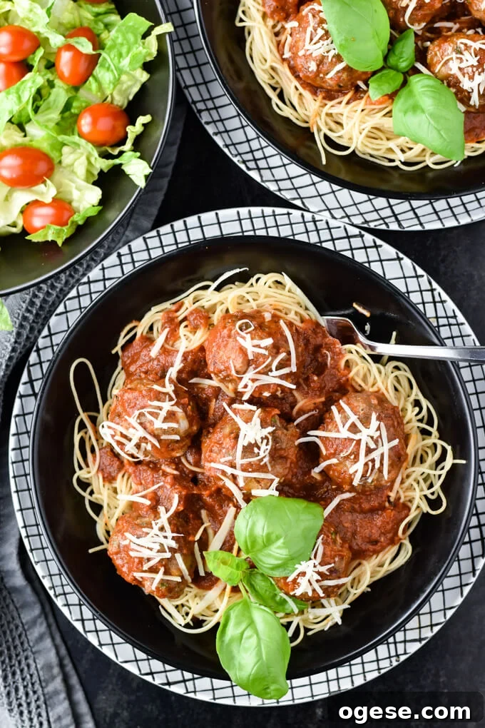 Authentic Homemade Pasta Sauce Recipe for Rich, Simple Flavor 8 A black bowl of homemade spaghetti and meatballs on a white checkered plate. A salad and another bowl of spaghetti and meatballs sit in the corner of the photo.