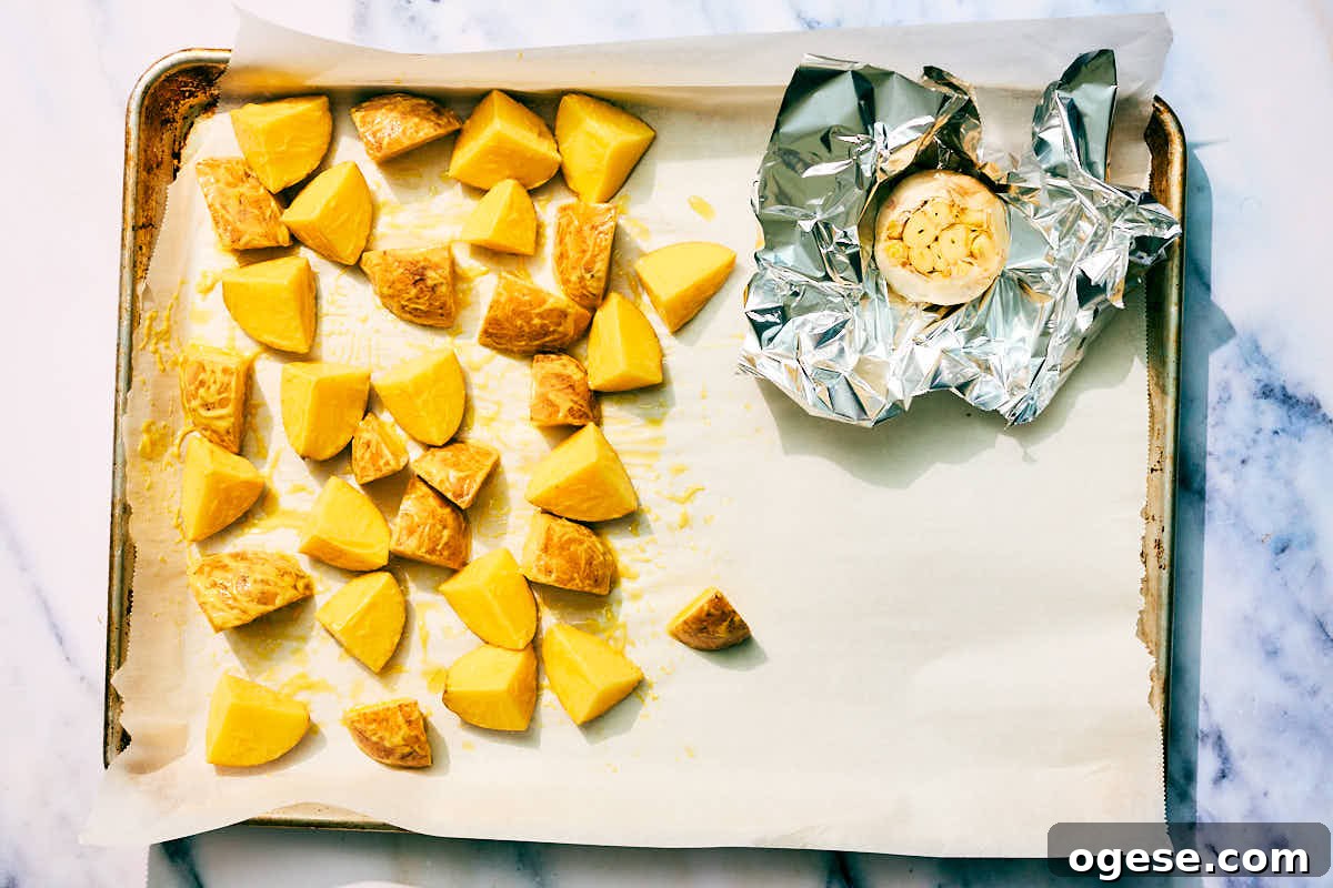 Potatoes and garlic on a baking sheet for roasting.