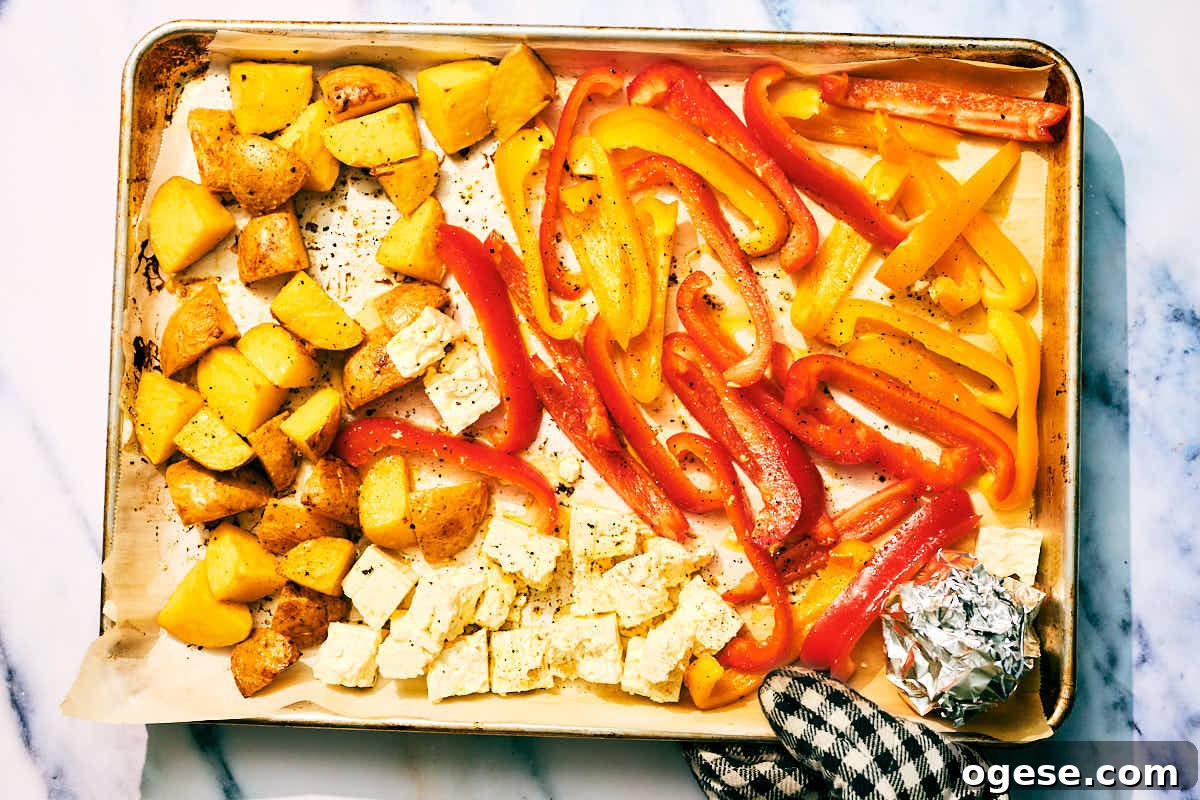 Feta, bell peppers, potatoes on a baking sheet to be roasted.