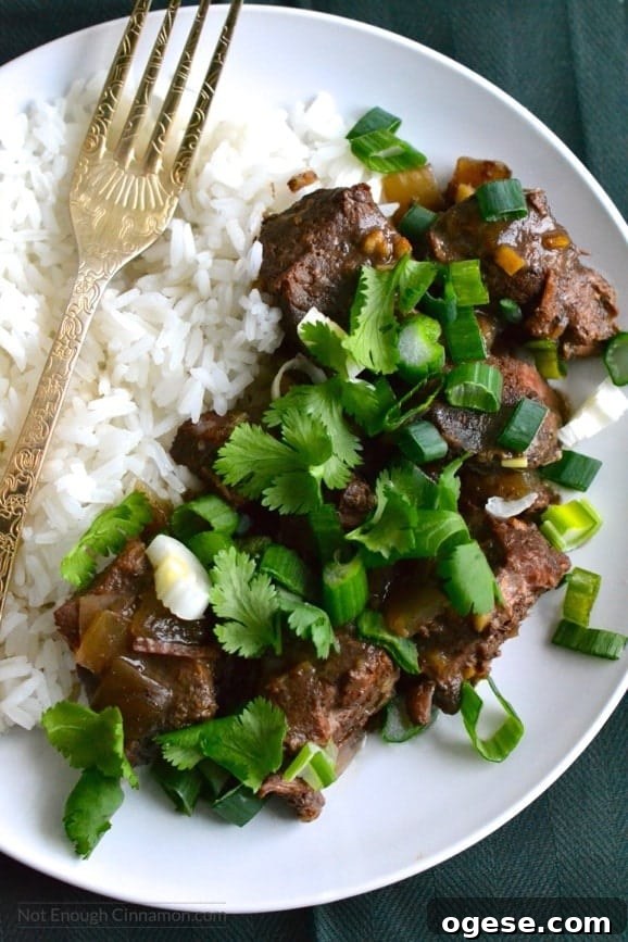 Slow Cooker Orange Ginger Beef Stew with Tender Chunks 3 close-up of a plate of slow cooker ginger beef served with a side of rice and some chopped cilantro