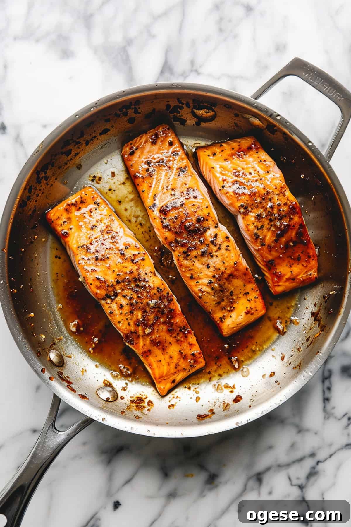 Maple glazed salmon in a pan with spices and sauce.