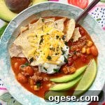a bowl of slow cooker taco soup topped with tortilla chips, sour cream and shredded cheese