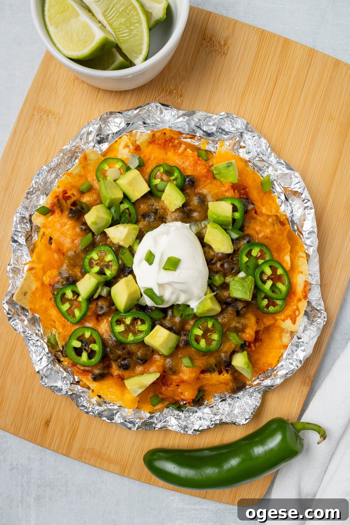 Crispy Air Fryer Nachos with Cheese & Quick Toppings 2 An overhead image of air fryer nachos with sou cream, sliced jalapenos, and avocados.