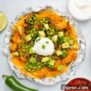 Crispy Air Fryer Nachos with Cheese & Quick Toppings 14 An overhead image of air fryer nachos with toppings like sour cream, jalapenos, and sliced avocados.