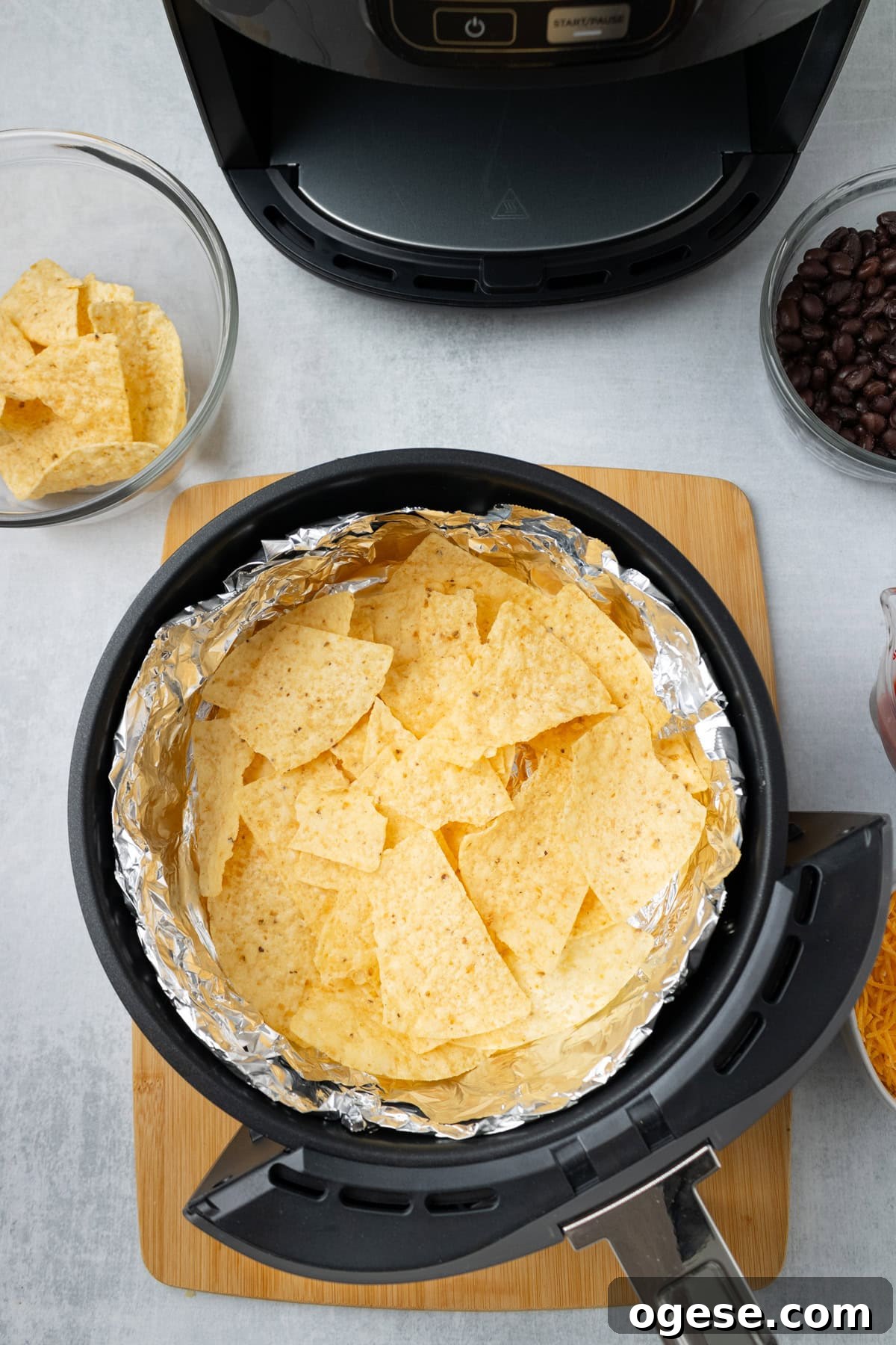 Crispy Air Fryer Nachos with Cheese & Quick Toppings 4 An overhead image of spreading tortilla chips in an air fryer lined with foil.