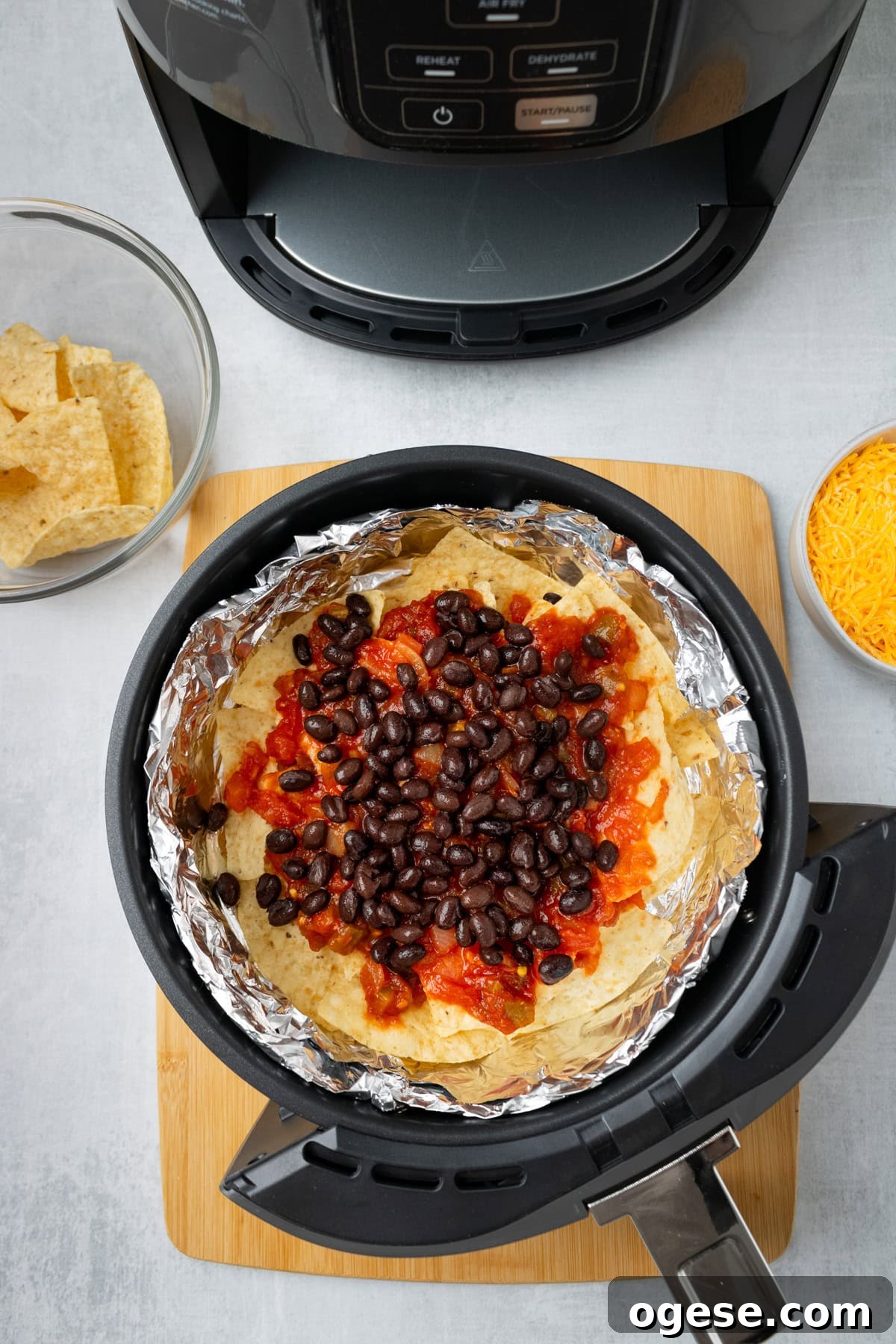 Crispy Air Fryer Nachos with Cheese & Quick Toppings 5 An overhead iamge of adding salsa and black beans in an air fryer.