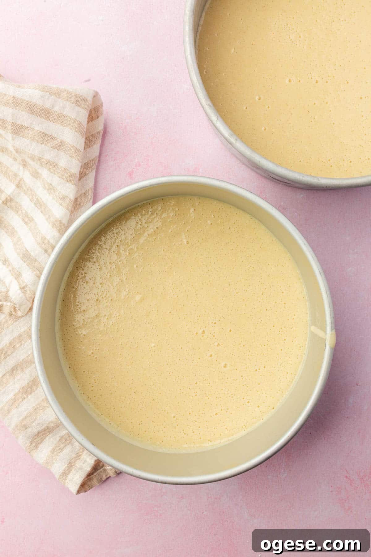 Two round 8-inch baking pans with gluten-free vanilla cake batter in them before baking in the oven.