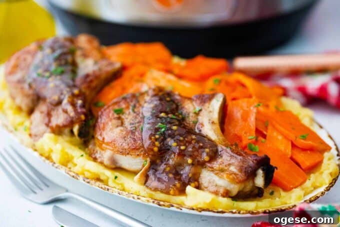 Instant Pot apple cider pork chops with carrots and mashed potatoes on a serving plate.