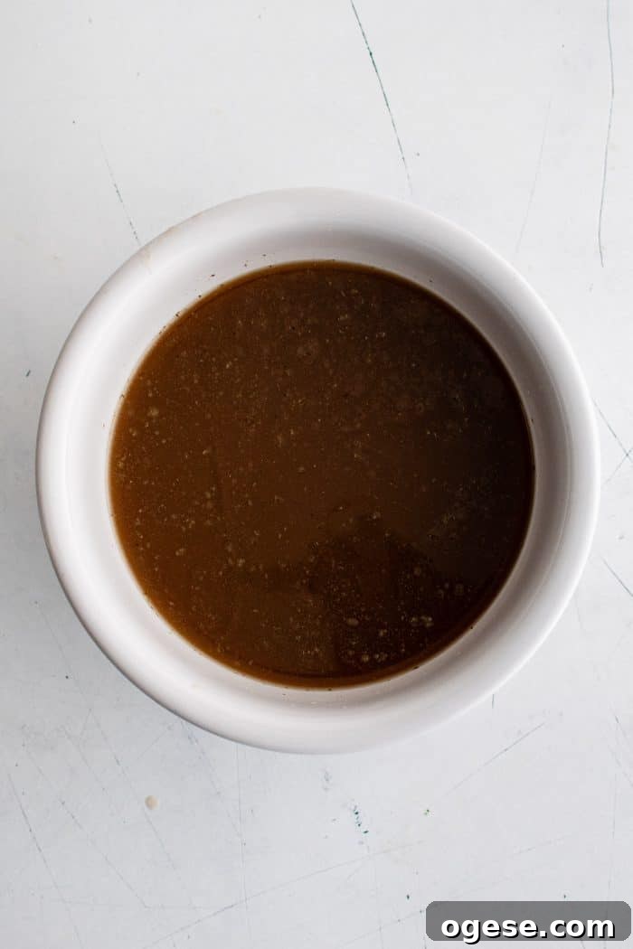 Classic Italian Beef Sandwich Recipe: Tender Slow-Cooked Roast Beef on Italian Bread 11 Large white bowl filled with au jus.