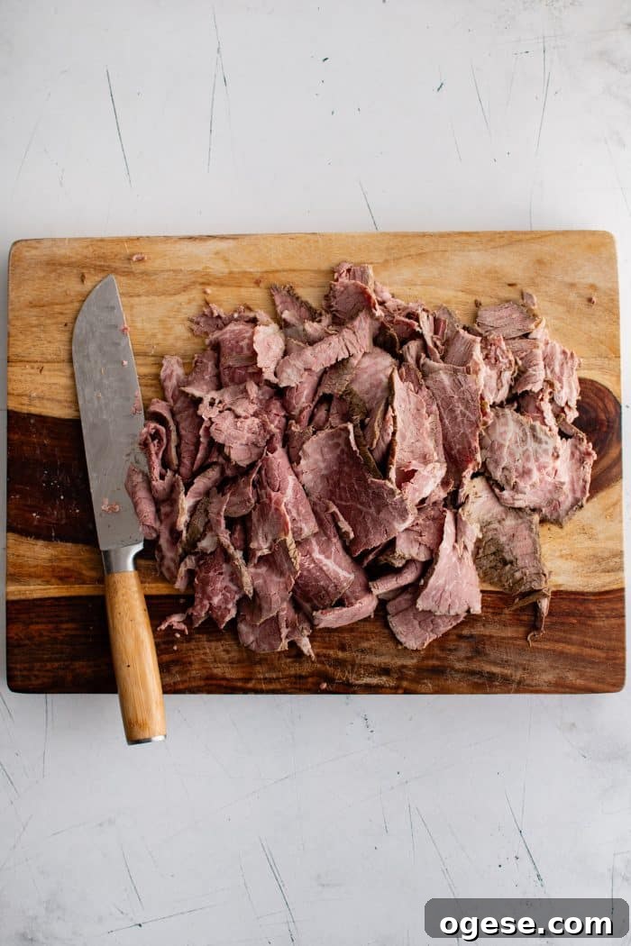Classic Italian Beef Sandwich Recipe: Tender Slow-Cooked Roast Beef on Italian Bread 12 Thinly sliced roast beef on a large cutting board.