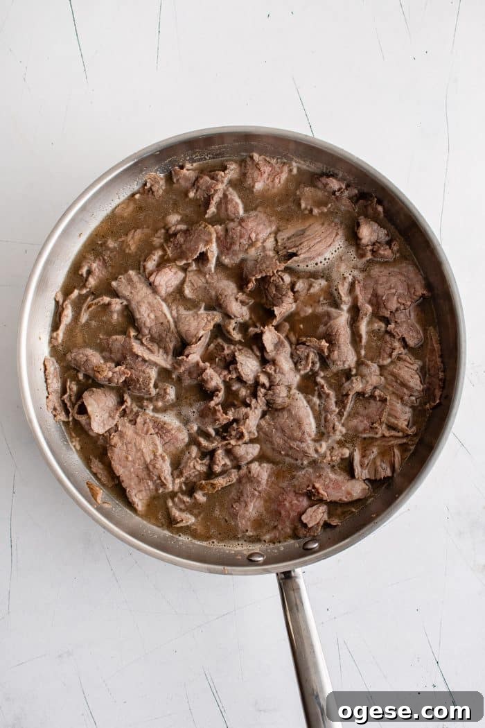 Classic Italian Beef Sandwich Recipe: Tender Slow-Cooked Roast Beef on Italian Bread 13 Large pan filled with thinly sliced Italian beef simmering in au jus.