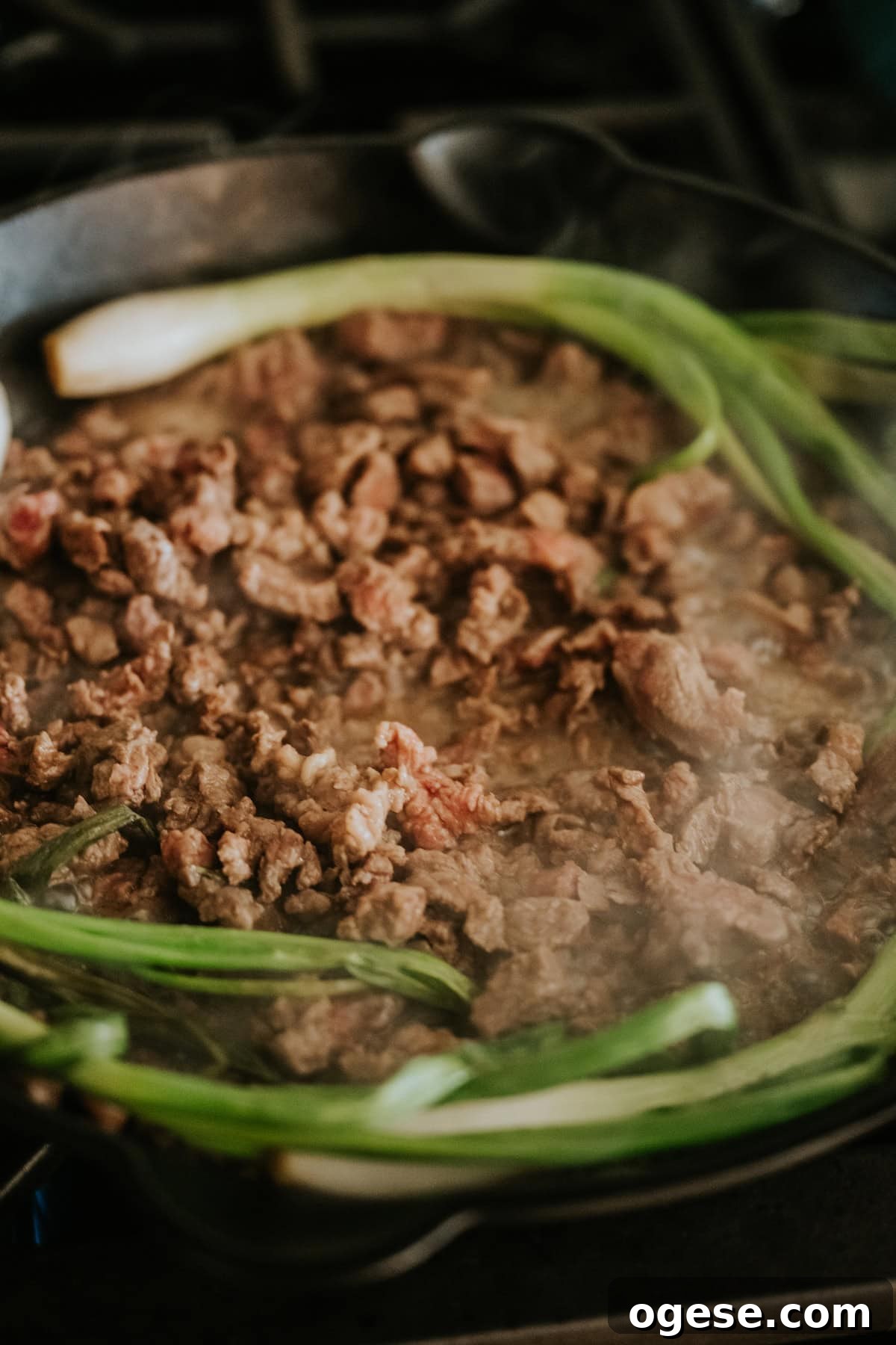 Seasoned taco meat cooked in a skillet with grilled cebollitas.