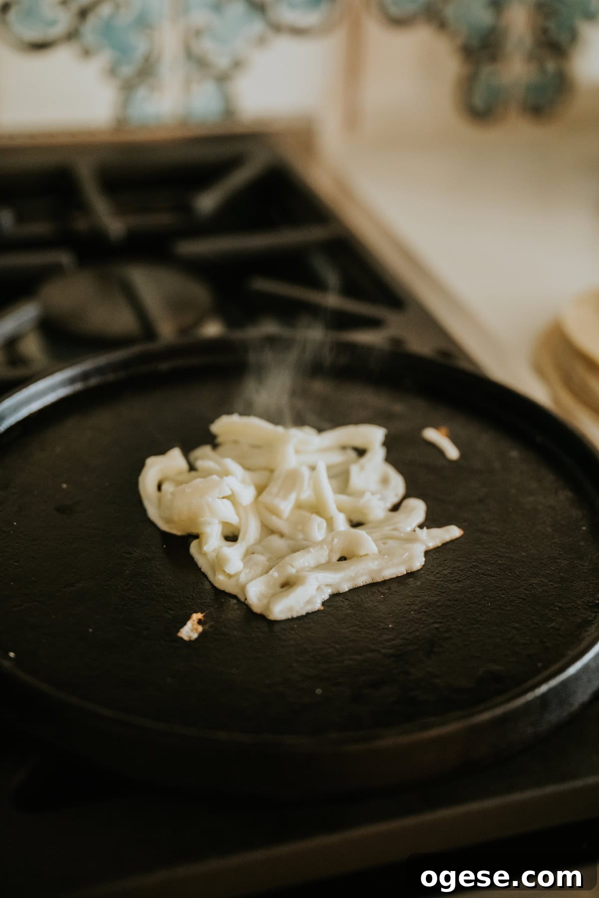 Oaxaca cheese melting on a comal until golden and bubbly.