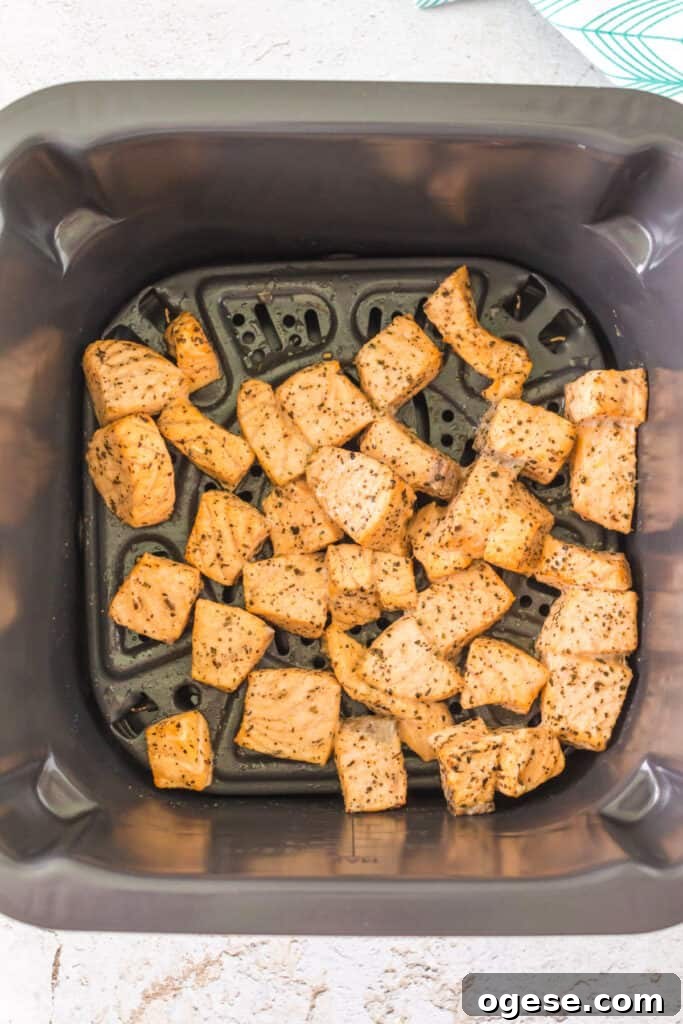 Cooked salmon bites in an air fryer basket showing golden color and crisp edges.