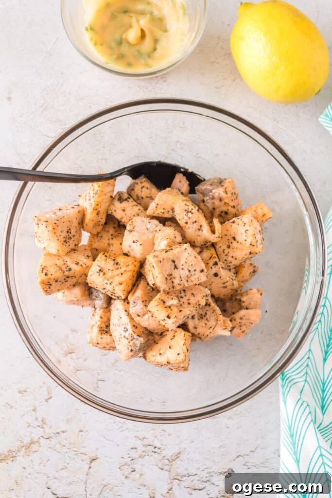 Bowl of freshly cooked salmon bites beside a lemon and bowl of garlic butter mixture.