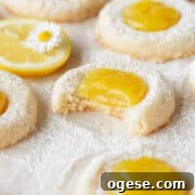 A bitten lemon curd cookie on a piece of parchment paper.