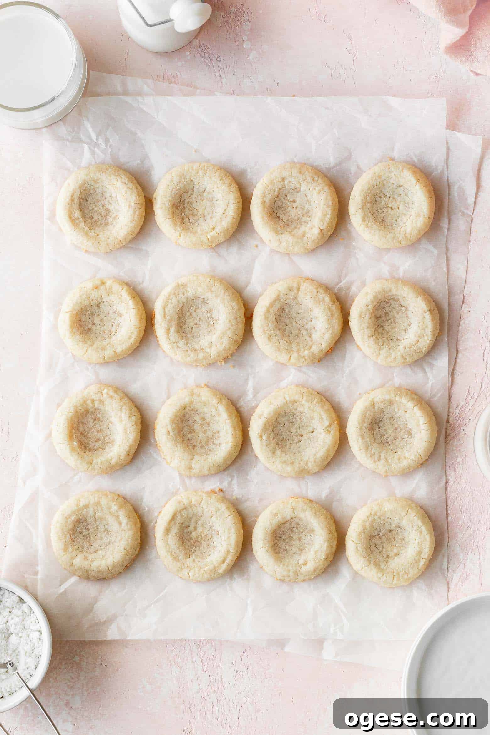 Sugar cookies with indentations on a piece of parchment paper.