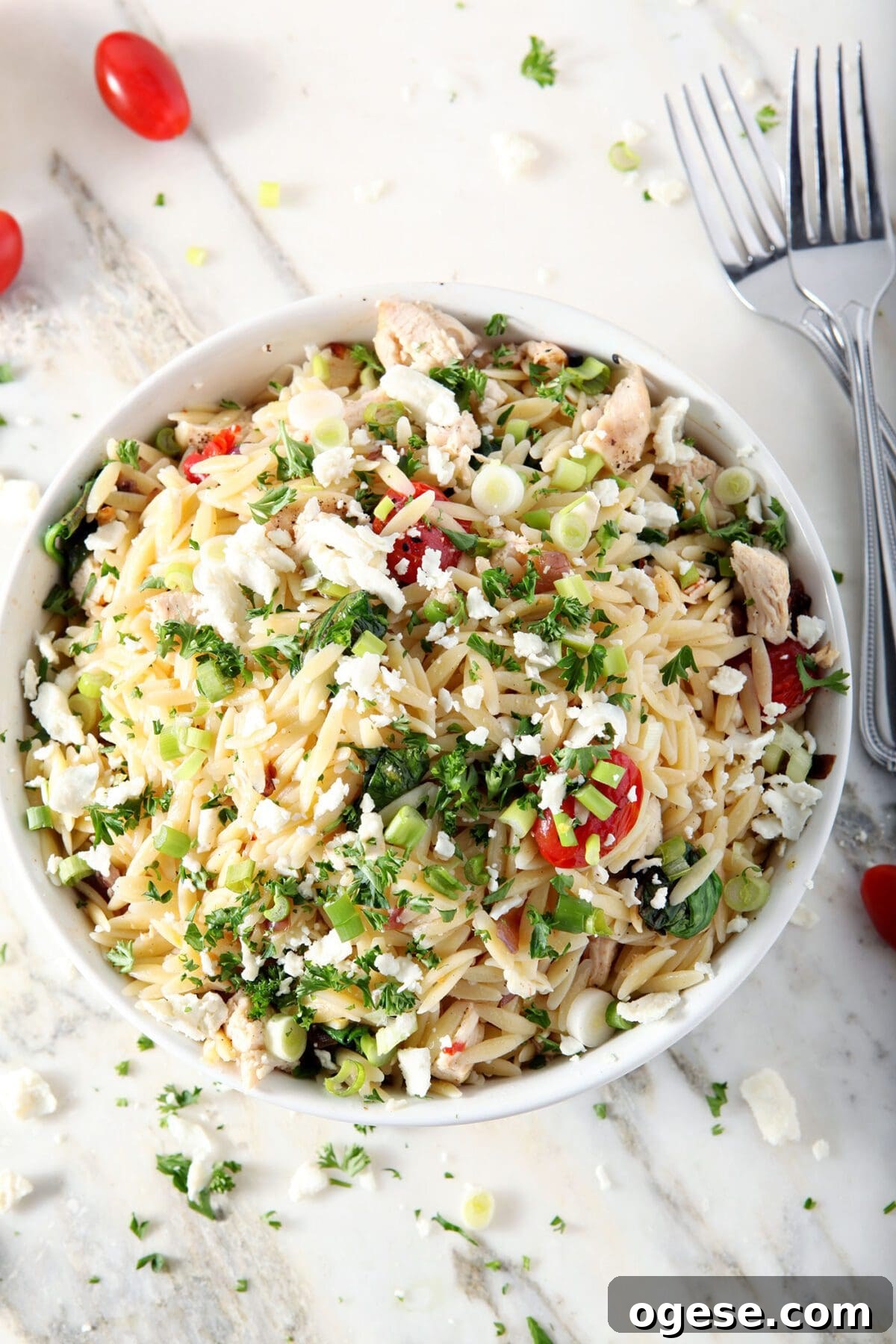 A bowl of lemon orzo pasta with chicken and veggies from above on a marble surface