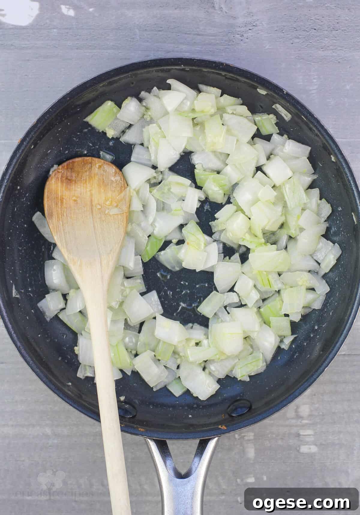 onion, garlic, and wood spoon in skillet