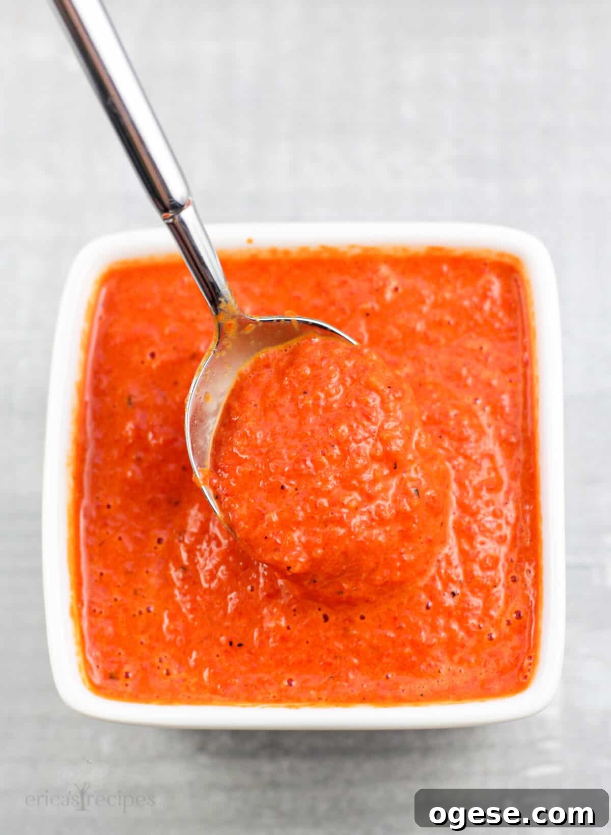 spoon holding coulis in small white bowl