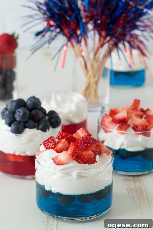 Patriotic 4th of July Fruit and Jello Cups Recipe 2 blue jello in glass cup topped with whipped cream and chopped strawberries
