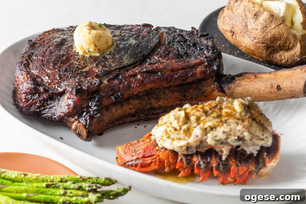 How to Cook a Tomahawk Steak Perfectly Every Time 4 cooked tomahawk steak topped with a scoop of compound butter on a plate with a cooked lobster tail. asparagus spears and a baked potato with butter in the background